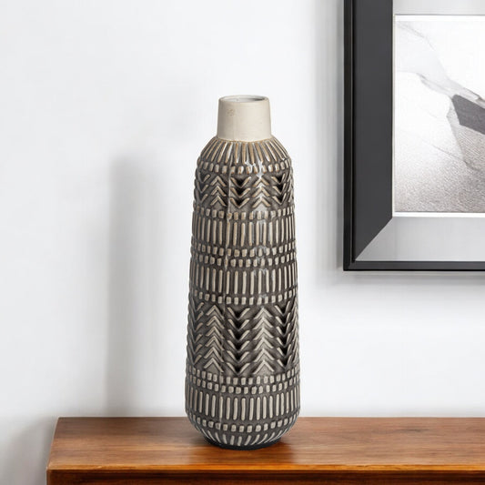 Decorative vase with geometric pattern on a wooden surface against a white wall.