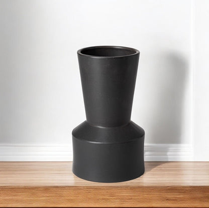 Black cylindrical vase on a wooden surface with a white background