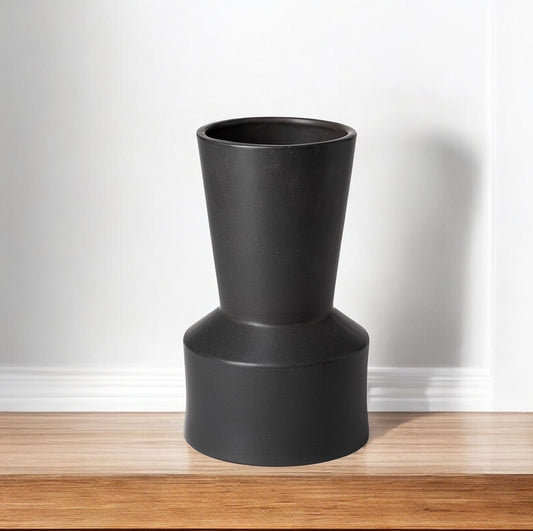 Black cylindrical vase on a wooden surface with a white background