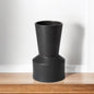 Black cylindrical vase on a wooden surface with a white background