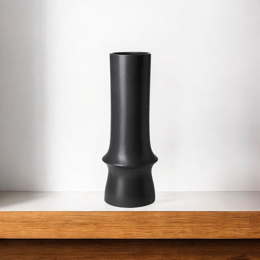 Black vase on a wooden shelf with a white background