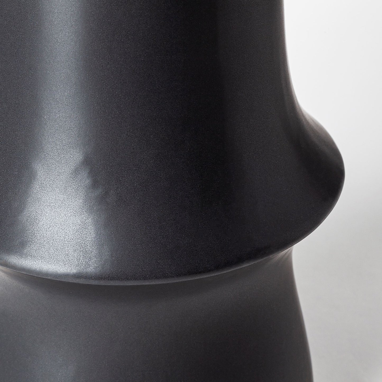 Close-up of a black ceramic vase on a light gray background