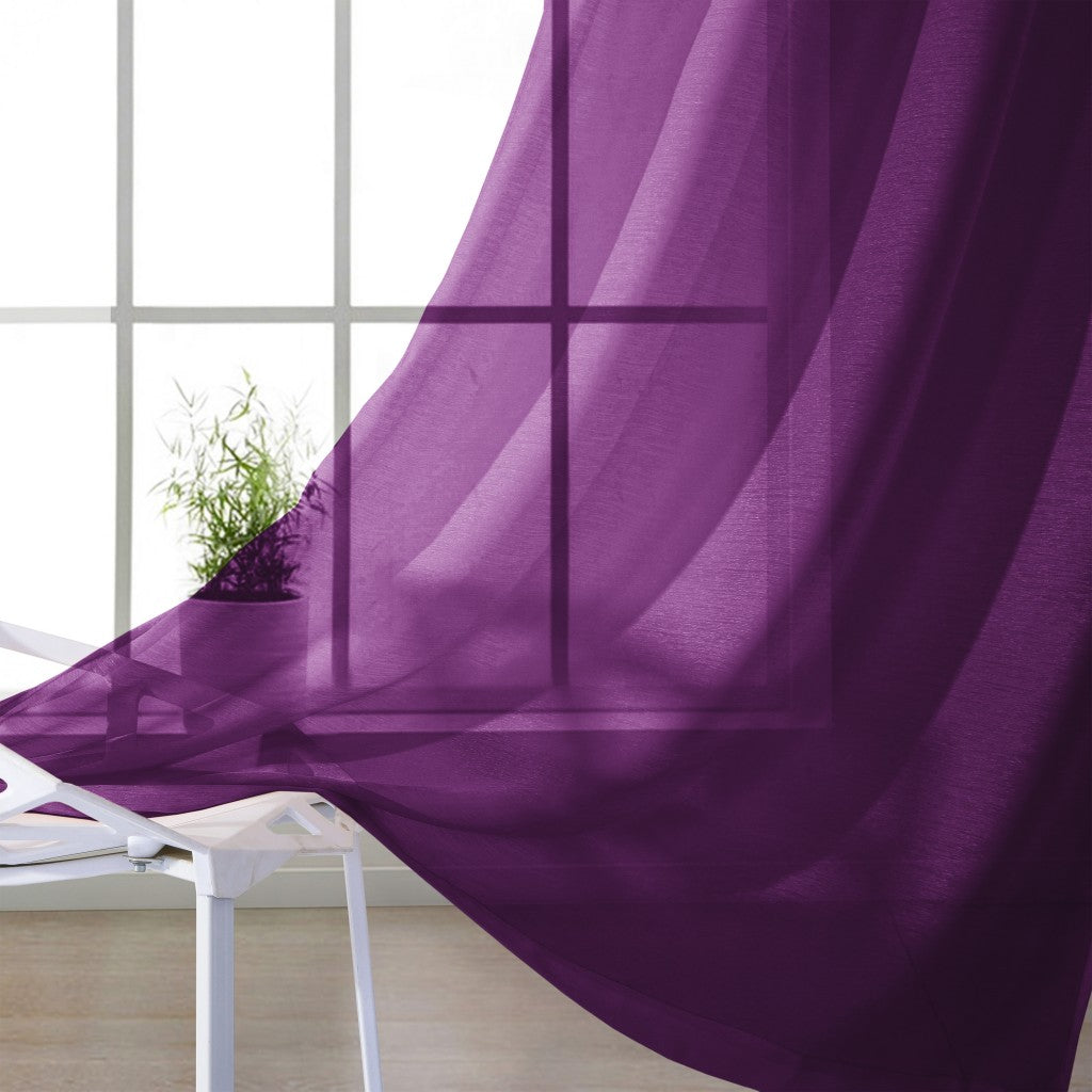 Purple sheer curtain in front of a window with a white chair and plant.