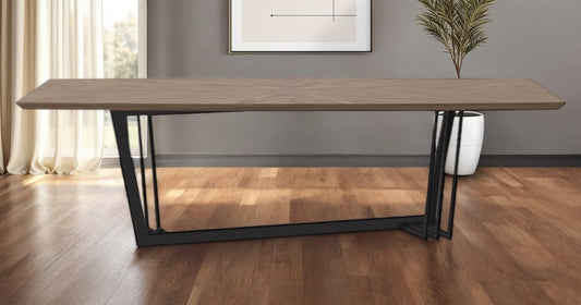 Wooden dining table with black metal legs in a room with a gray wall and window.