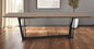 Wooden dining table with black metal legs in a room with a gray wall and window.