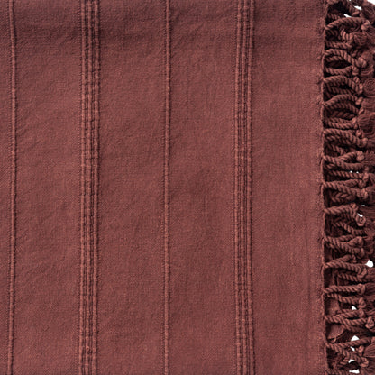 Close-up of a maroon fabric with textured pattern and frayed edge