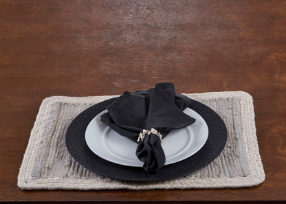 White plate with black napkin on a textured placemat, all on a wooden surface
