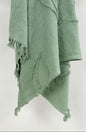 Green textured blanket with frayed edges on a white background