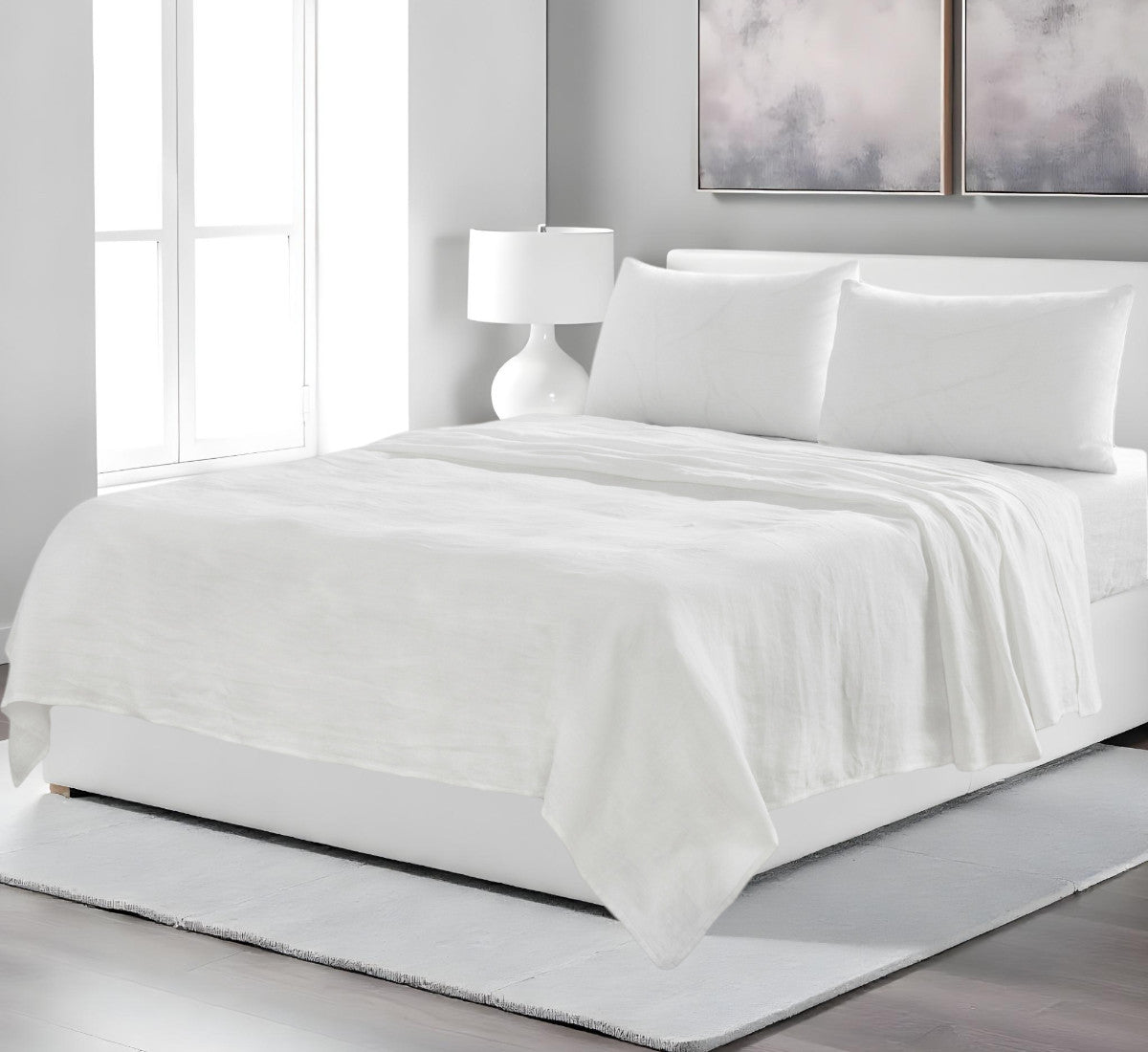 White bedding set on a bed in a modern bedroom with abstract art on the wall.