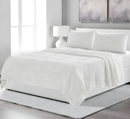 White bedding set on a bed in a modern bedroom with abstract art on the wall.