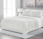 White bedding set on a bed in a modern bedroom with abstract art on the wall.