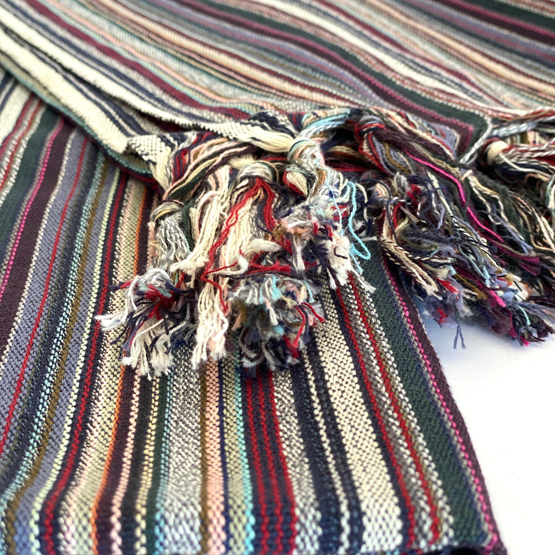 Close-up of a striped fabric with tassels on a white background