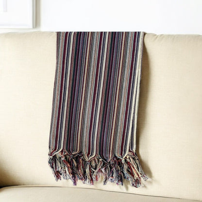 Striped blanket with tassels draped over a beige sofa