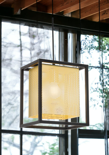 Modern pendant light with a geometric design in a room with large windows.