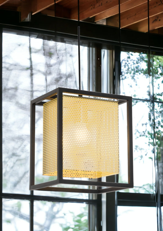 Modern pendant light with a geometric design in a room with large windows.
