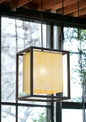 Modern pendant light with a geometric design in a room with large windows.