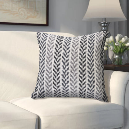 Decorative pillow with a geometric pattern on a white couch in a living room setting.