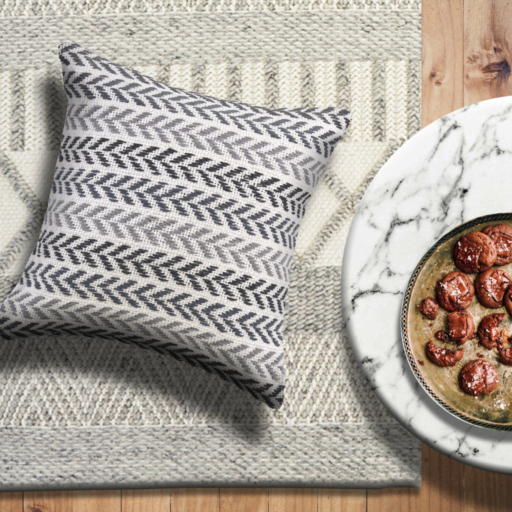 Patterned pillow on a textured rug with a plate of food on a marble surface.