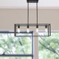 Modern black chandelier with four light bulbs hanging in a room with large windows.