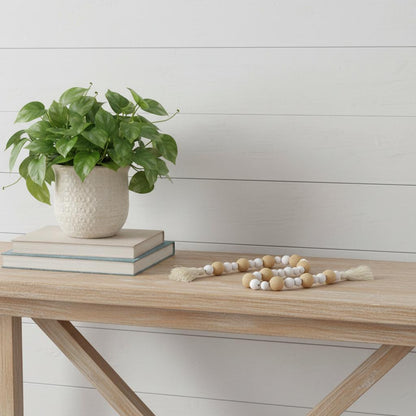 Potted plant on books with a decorative item on a wooden table against a light background